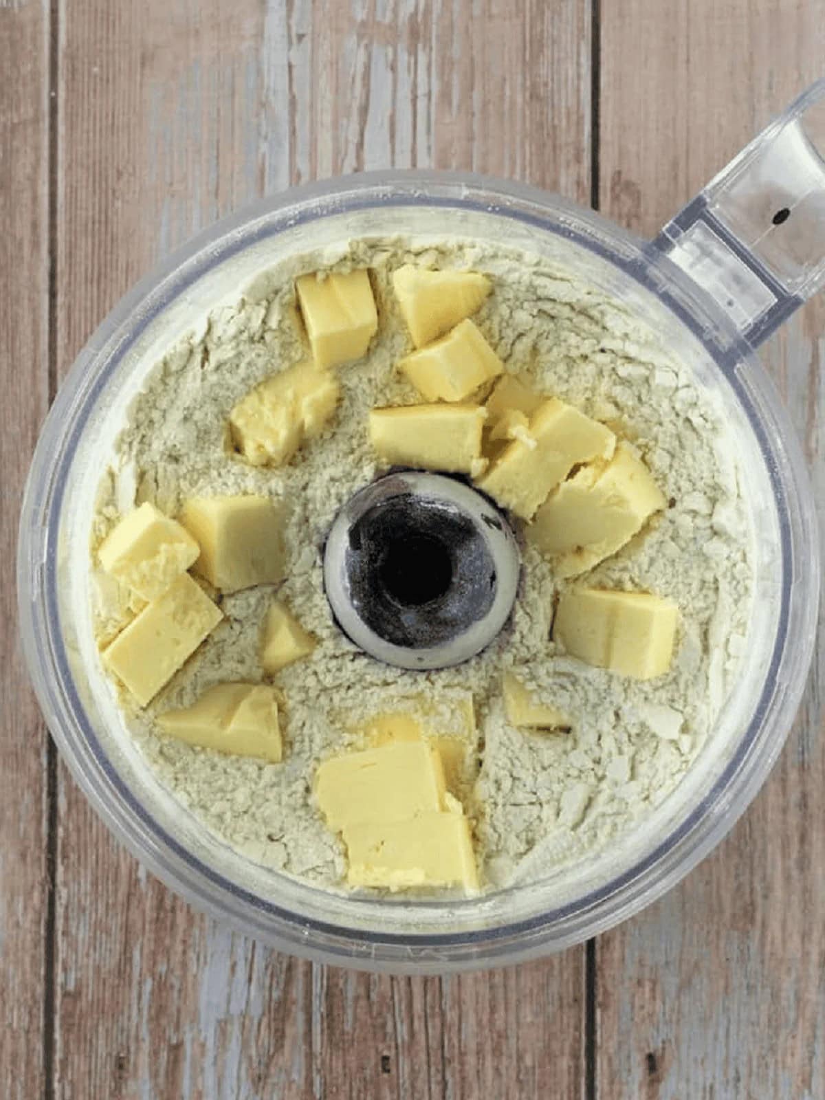 Cubed butter added to food processor bowl with dry ingredients for Settembrini cookie dough.