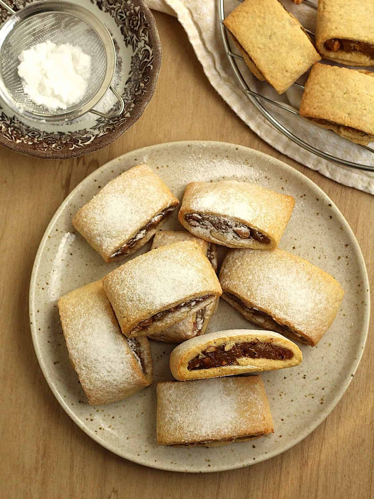 Shortcrust cookies with fig jam filling topped with powdered sugar on plate.