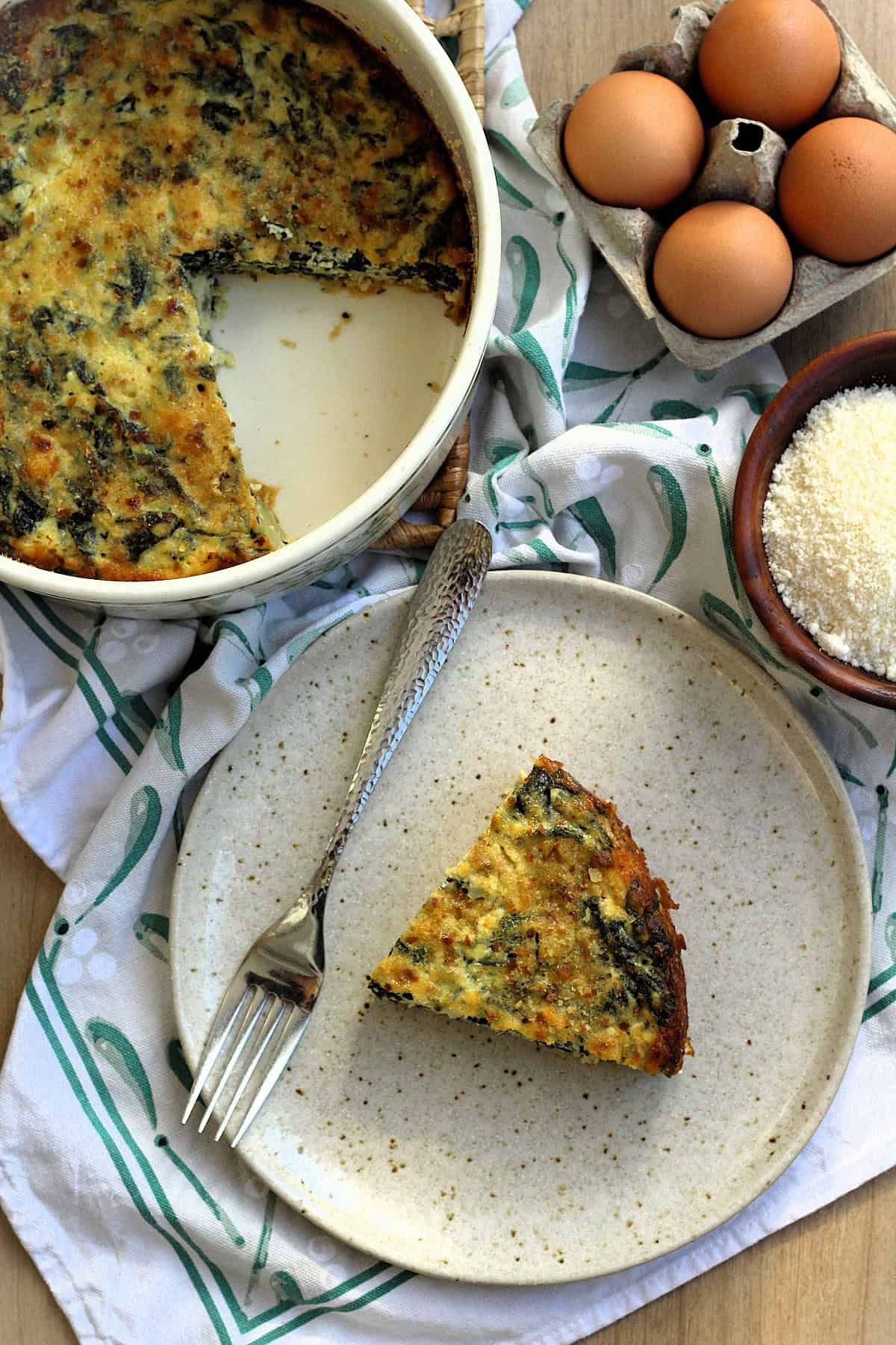 Wedge of swiss chard and ricotta bake on plate with fork next to casserole dish.