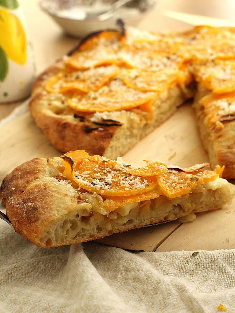 Slice of butternut squash pizza with caramelized onions and ricotta salata.