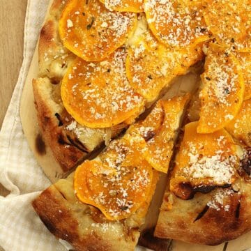 Butternut squash pizza with caramelized onions with wedge cut out.