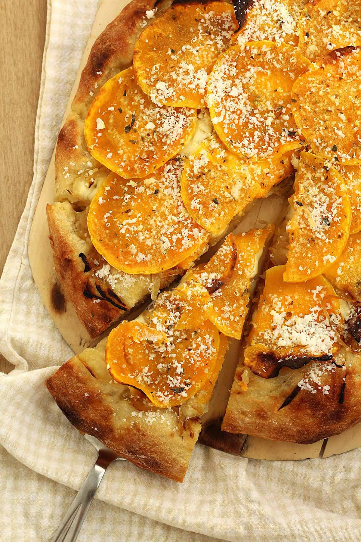 Butternut squash pizza with caramelized onions with wedge cut out.