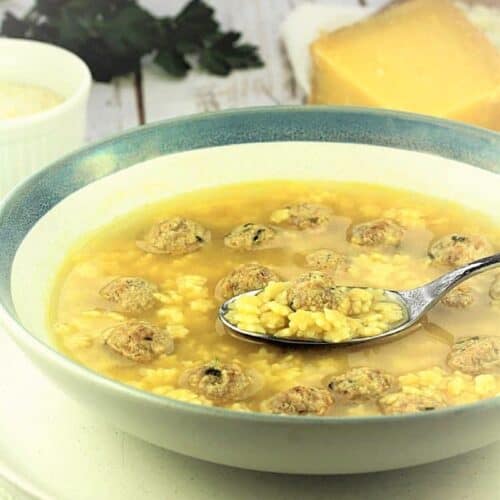 Spoonful of pastina soup with small meatballs in bowl.