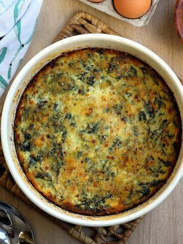 Swiss chard and ricotta bake with eggs and cheese in casserole dish topped with crips breadcrumbs.