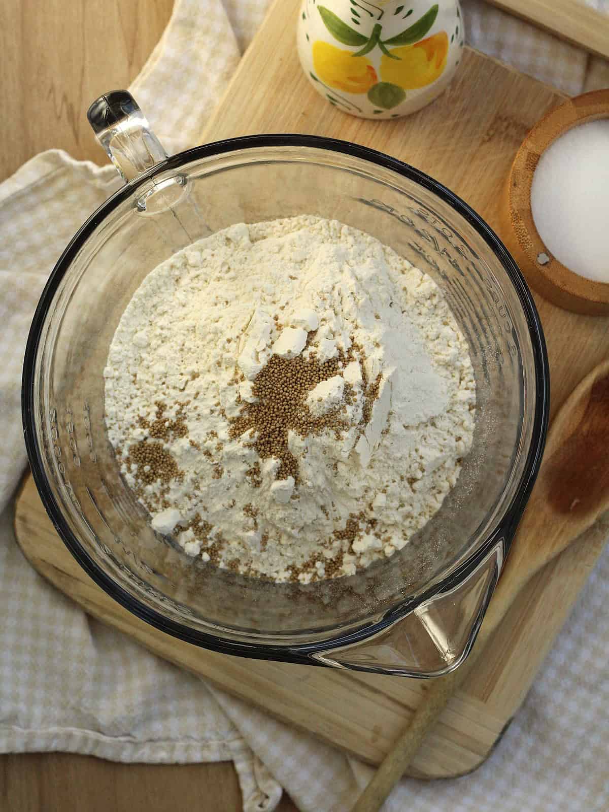 All purpose flour and active dry yeast stirred together in bowl for no knead pizza dough.