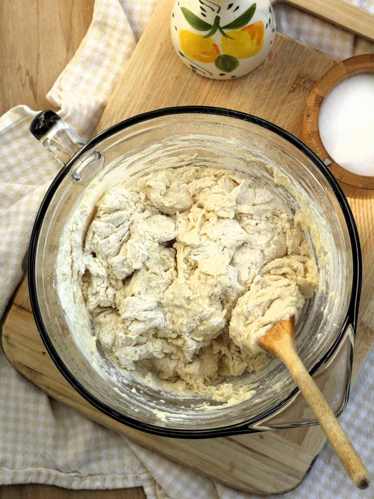 Water stirred into flour-yeast mixture with wood spoon for no-knead pizza dough.