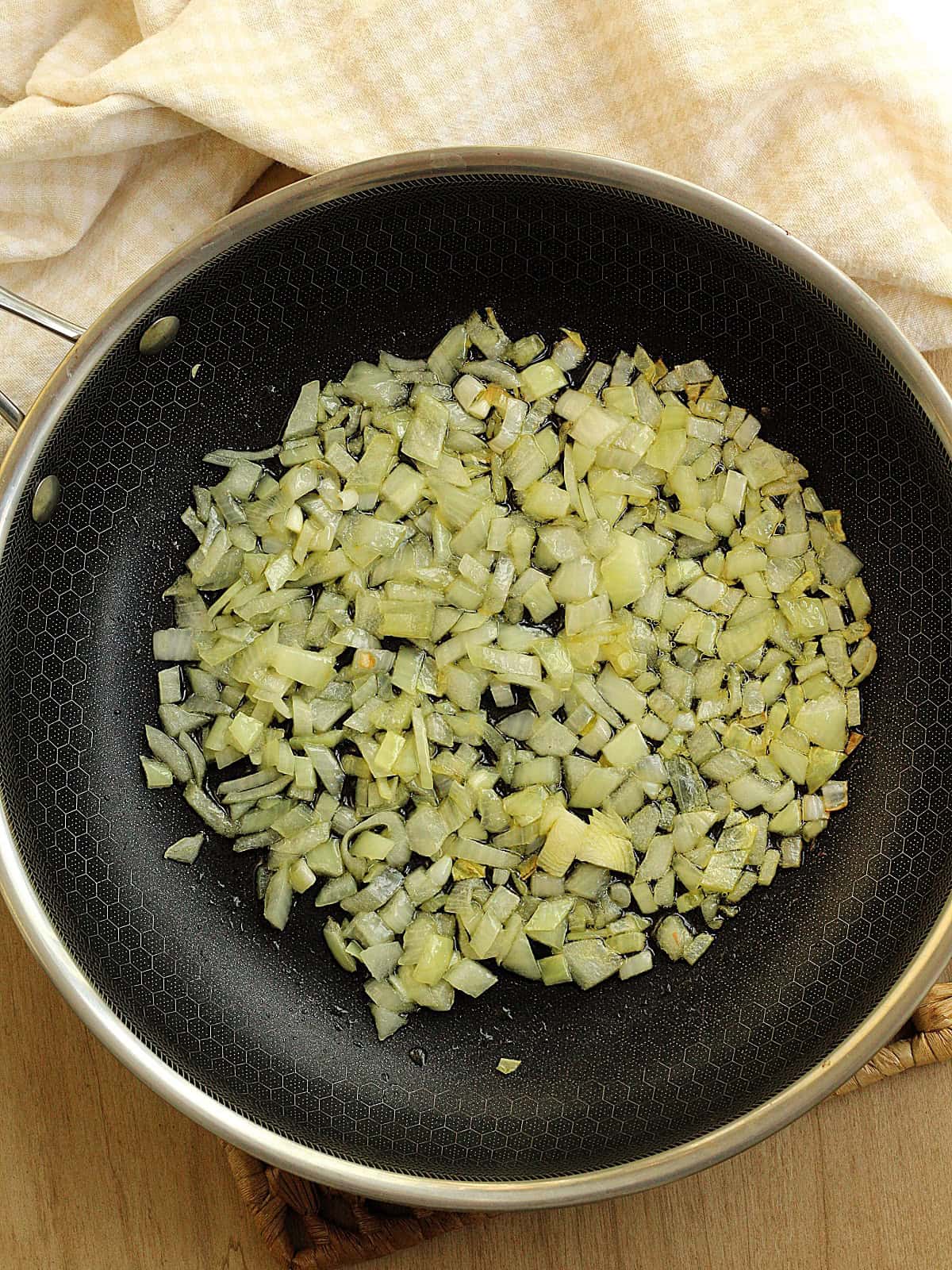 Sautéed diced onion in skillet for swiss chard tortino recipe.