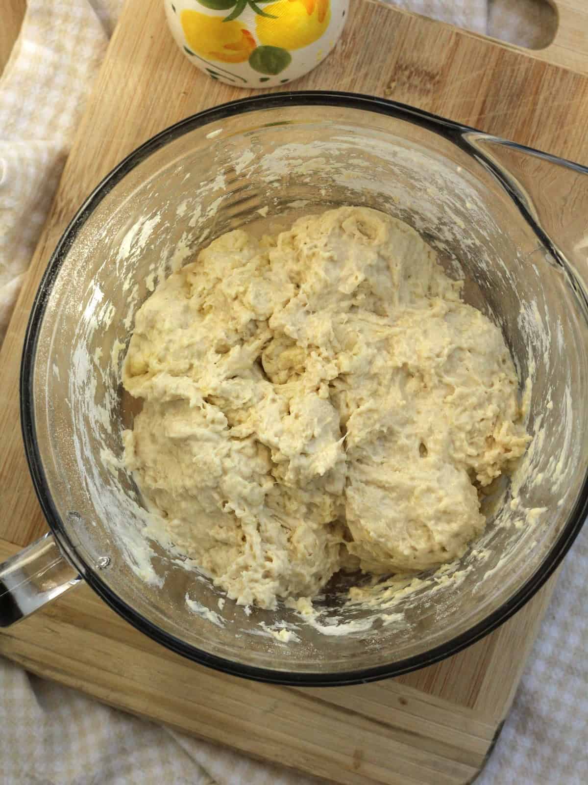Shaggy no knead pizza dough in glass bowl for squash pizza recipe.