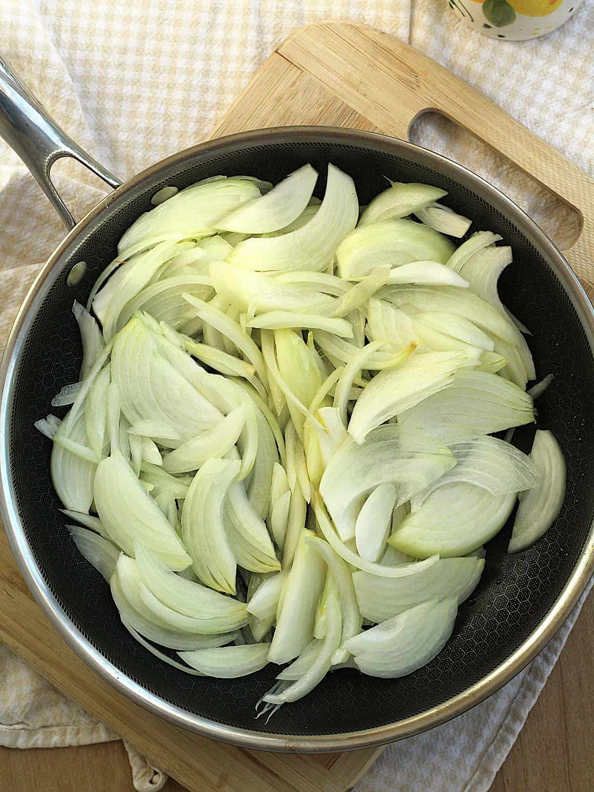Thinly sliced onions in skillet to be caramelized for pizza topping.
