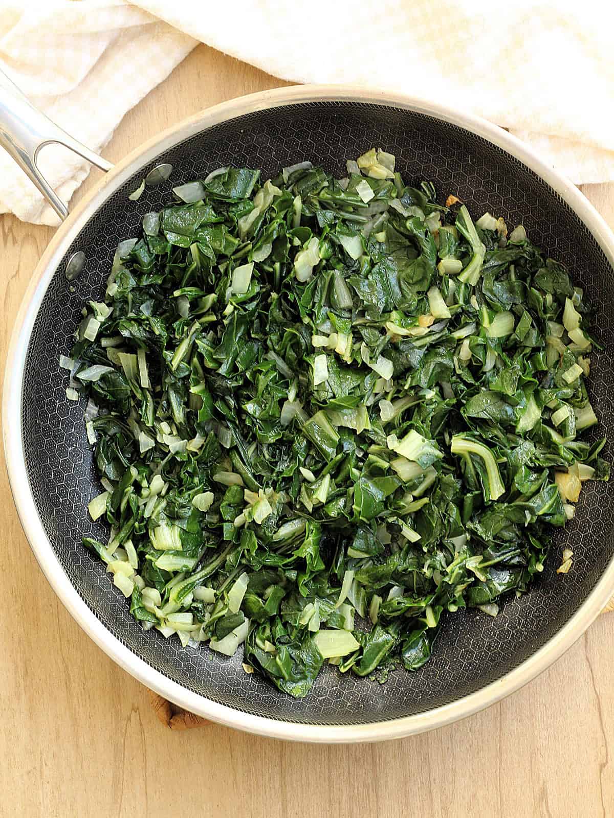 Sautéed swiss chard and onion in skillet for swiss chard bake recipe.