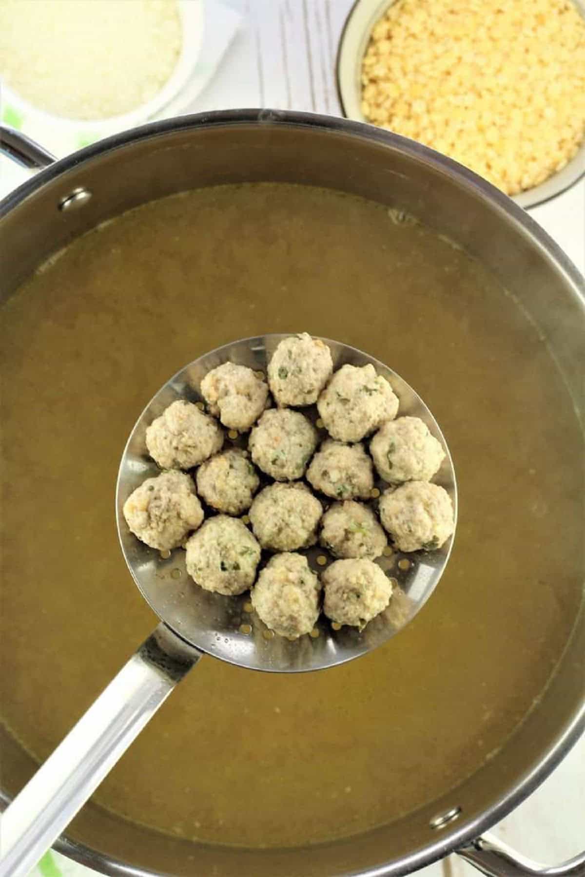 Tiny meatballs being added to sauce pan with hot chicken broth.