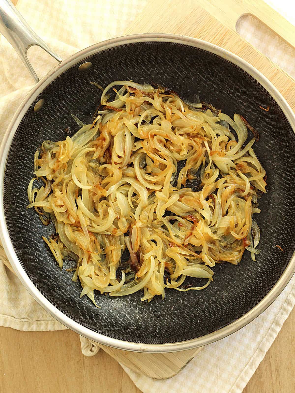 Caramelized onions in skillet for butternut squash pizza.