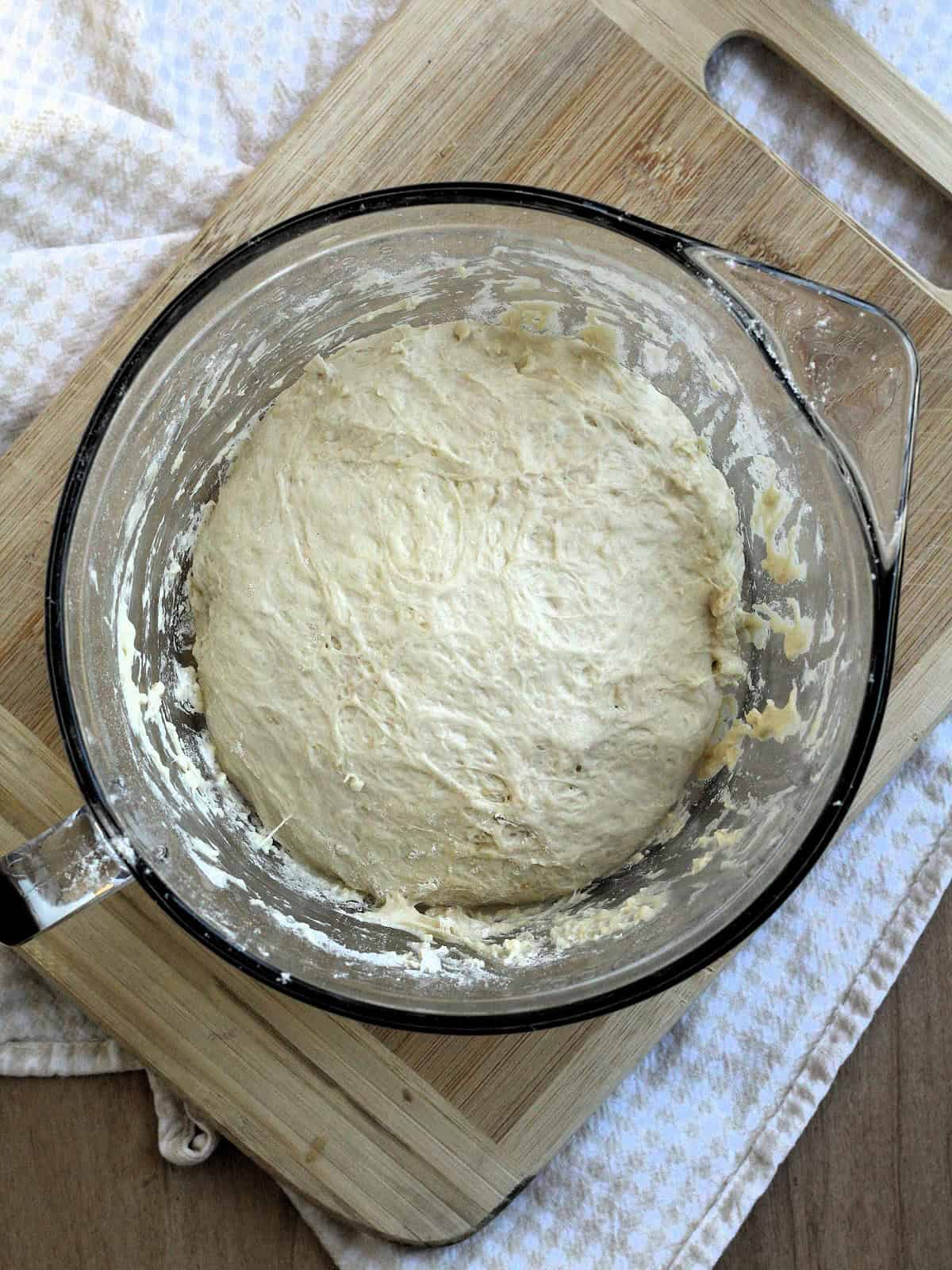 Ball of no knead dough in bowl for pizza with butternut squash recipe.