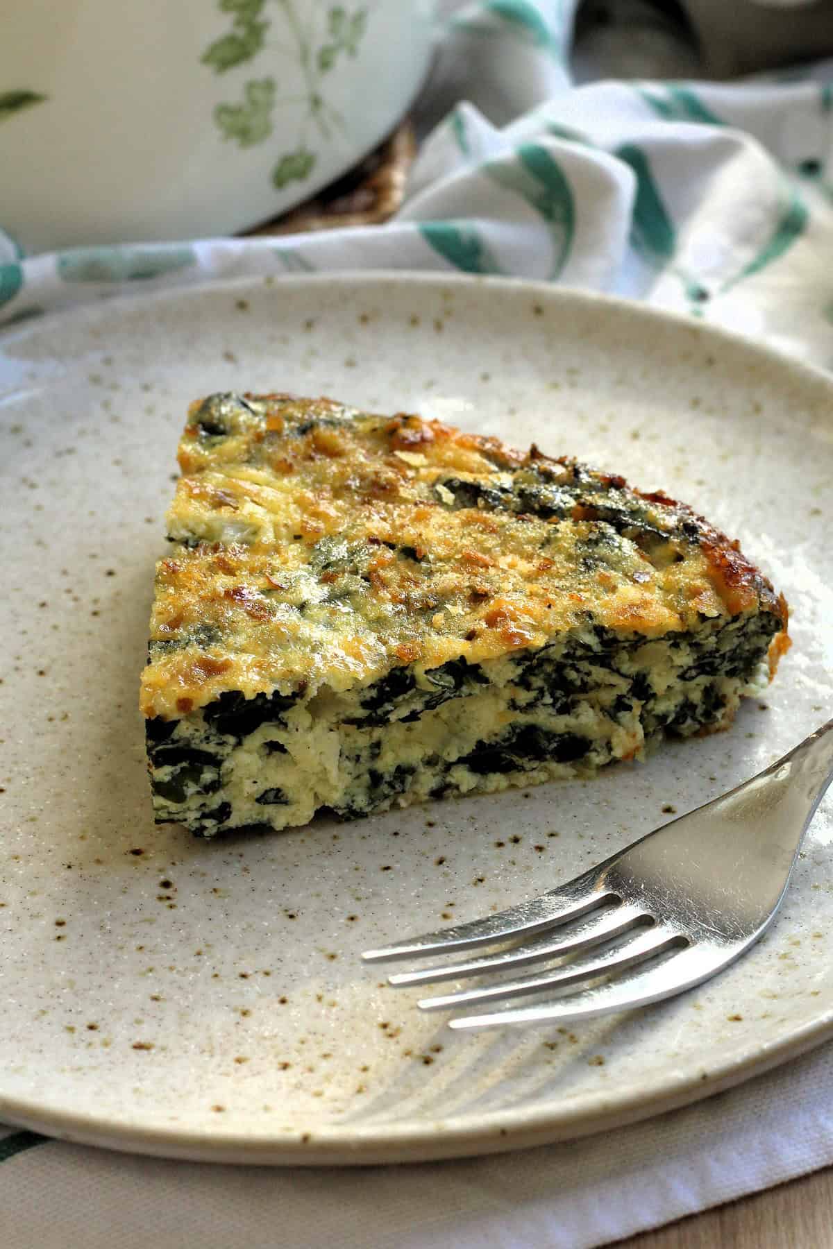 Wedge of swiss chard and ricotta crustless tart on plate with fork.